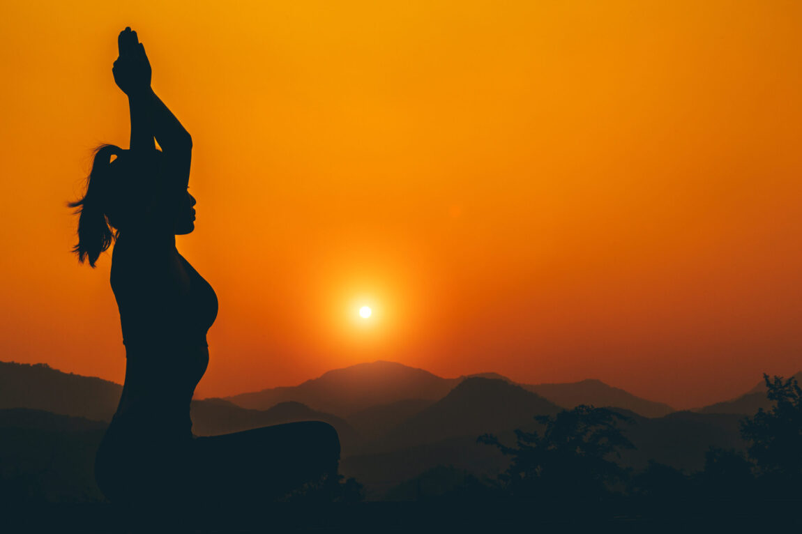 Silhouette – Yoga girl is practicing on the rooftop while sunset